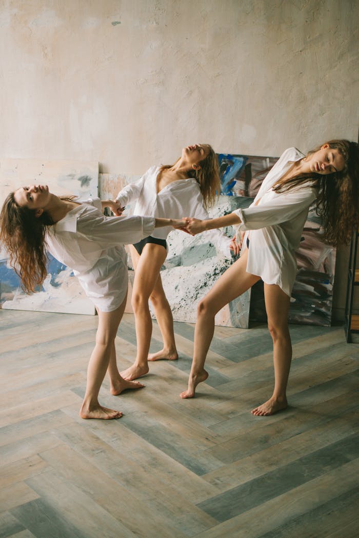 A trio of women elegantly dance in an artistic studio, showcasing graceful movement and creative expression.